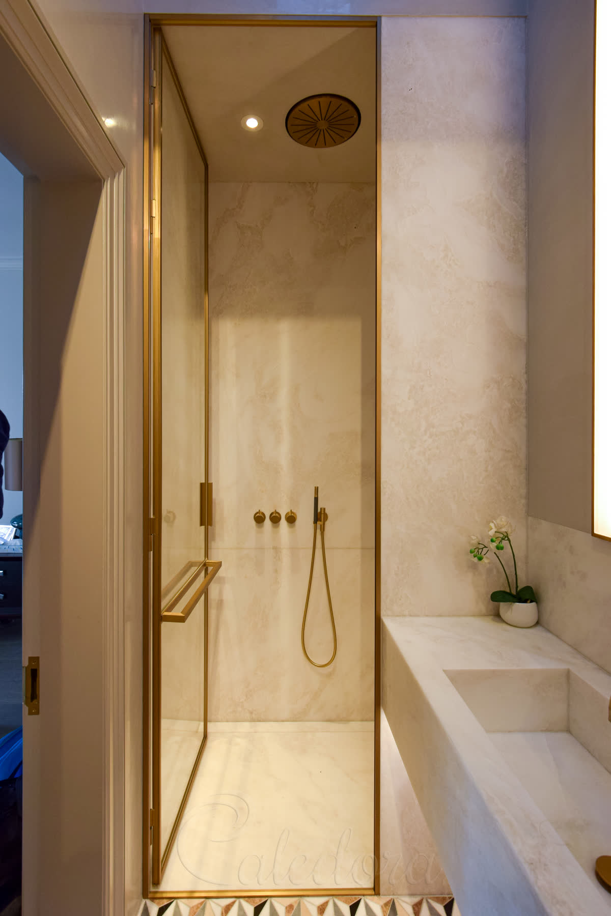 Custom L-shaped brass handle and towel rail fixed to ultra clear shower glass