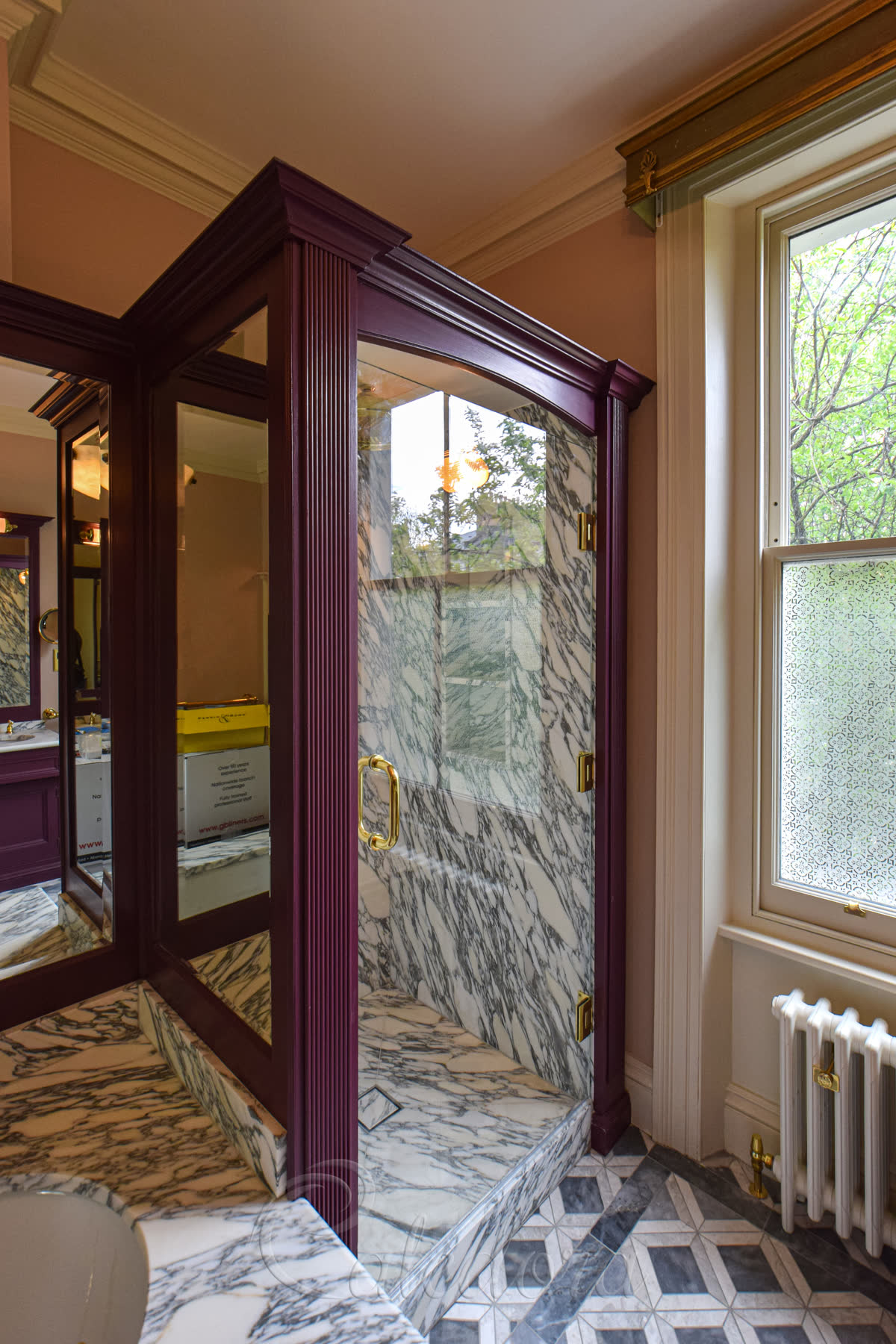 Frameless swing brass shower door on marble bespoke shower tray and timber frame