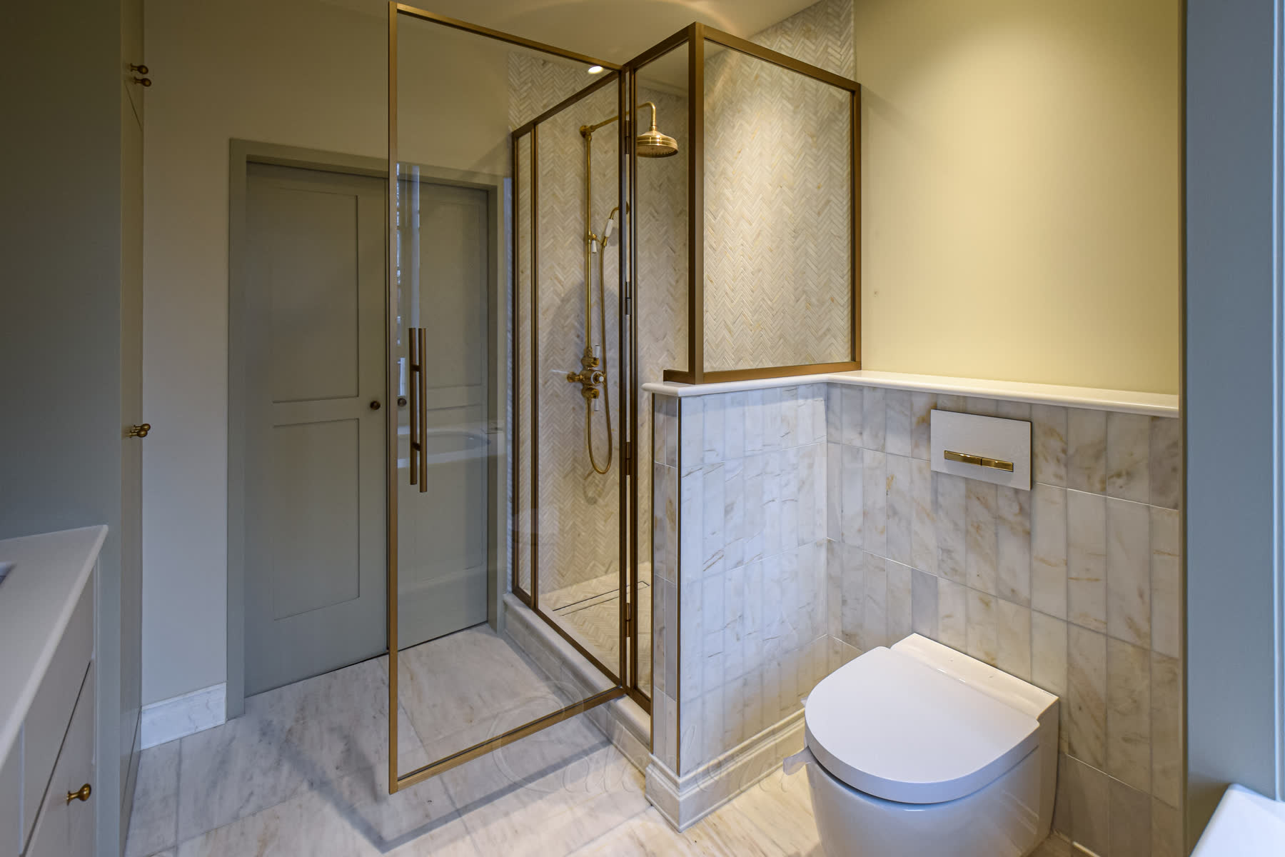 Custom corner brass shower enclosure following marble stone lines with bespoke shape