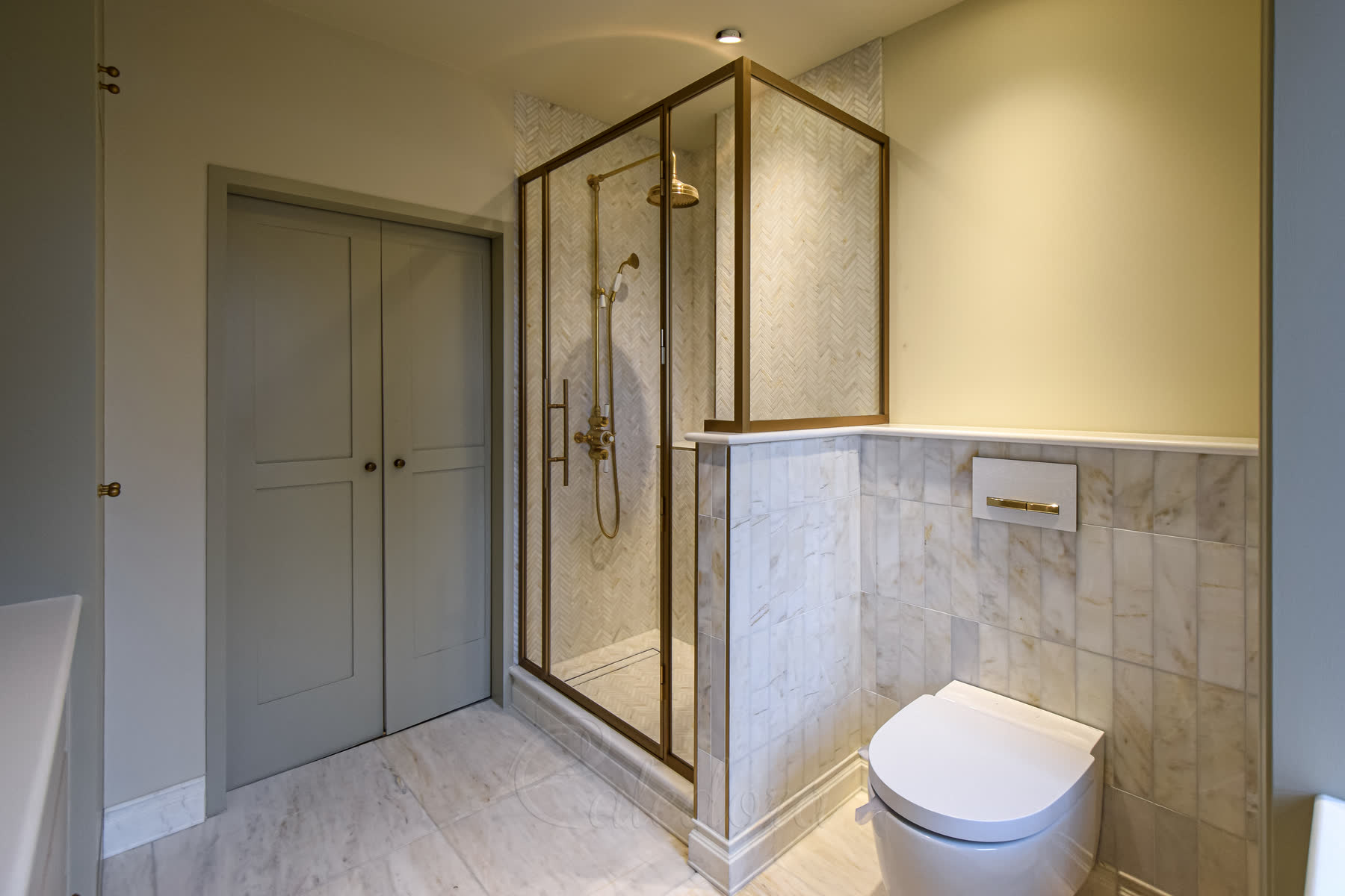 Aged brass shower frame recessed into shaped marble stone wall