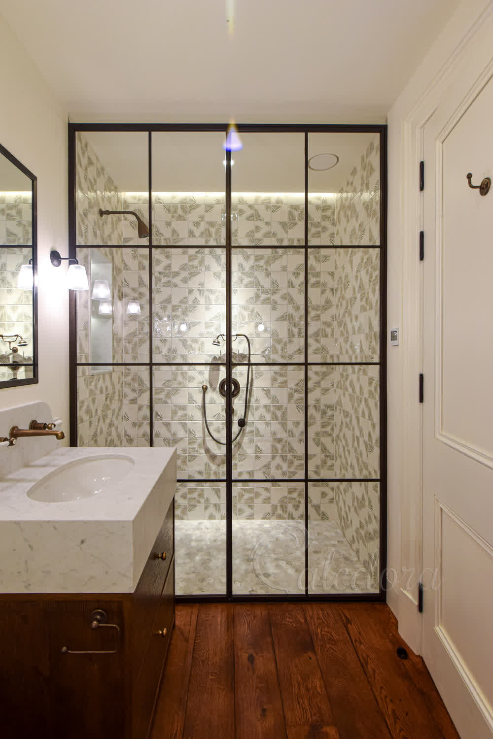 Bronze grid shower enclosure with inward-opening door, traditional knob and clean glass detailing