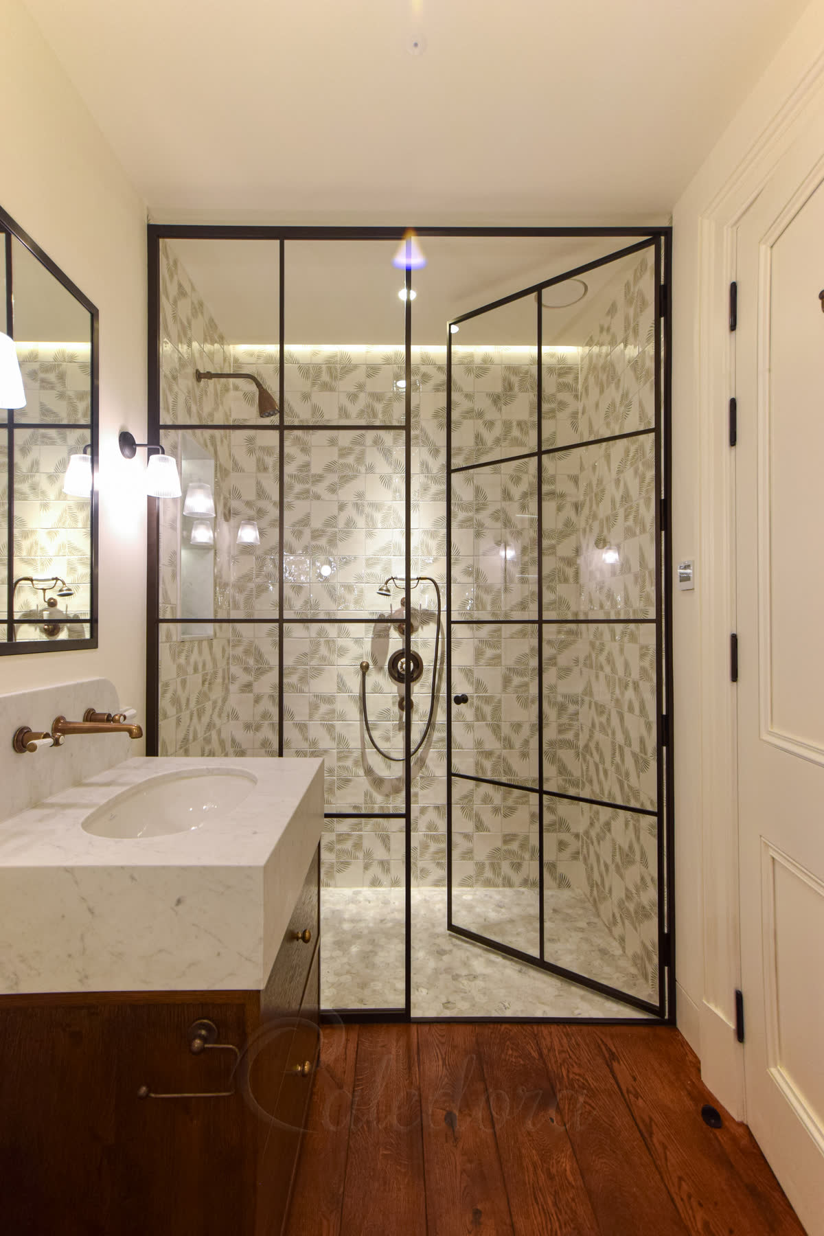 Bronze grid frame shower enclosure with traditional knob and tile-to-floor sealing detail