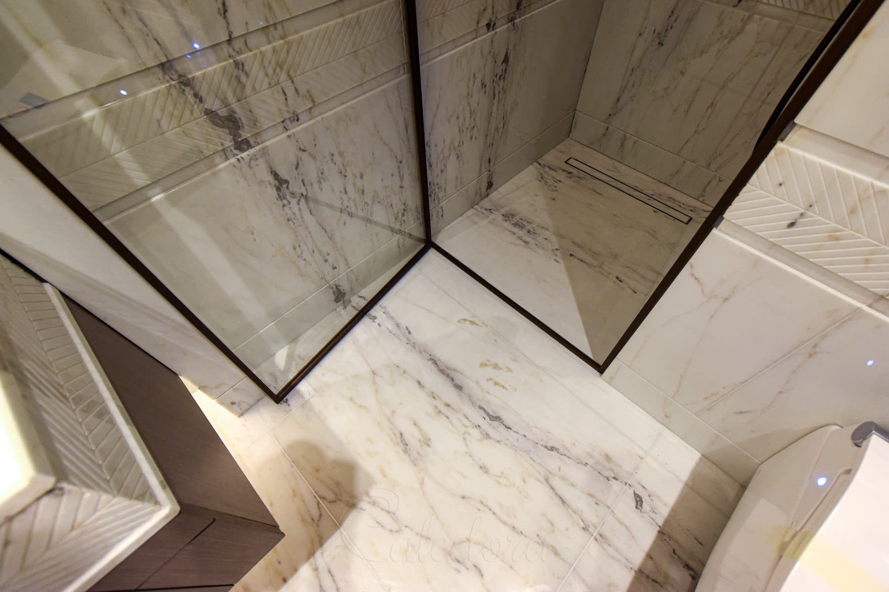 Close-up view of bronze shower door frame against marble floor and walls