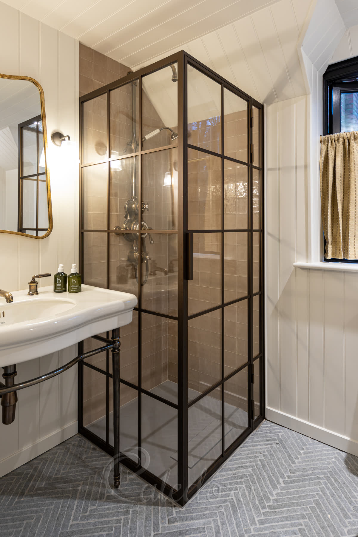 Corner bronze shower enclosure with grid design installed between tiled walls and wooden panelling