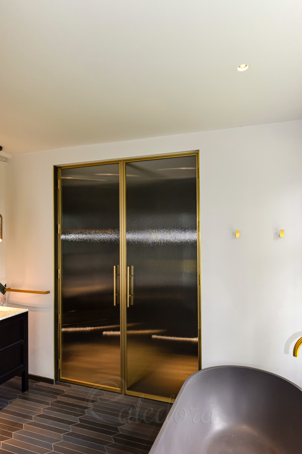 Side angle view of brushed brass shower doors with vertical fluted glass pattern