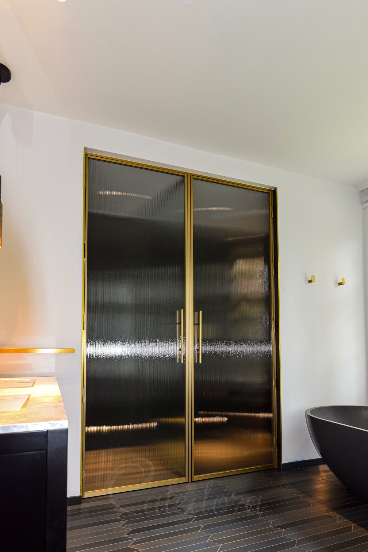 Left perspective of brass framed shower doors showing the warm metallic finish
