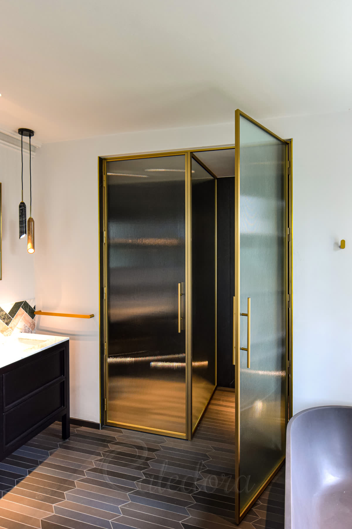 Right side view of open shower door with brass frame and fluted glass partition