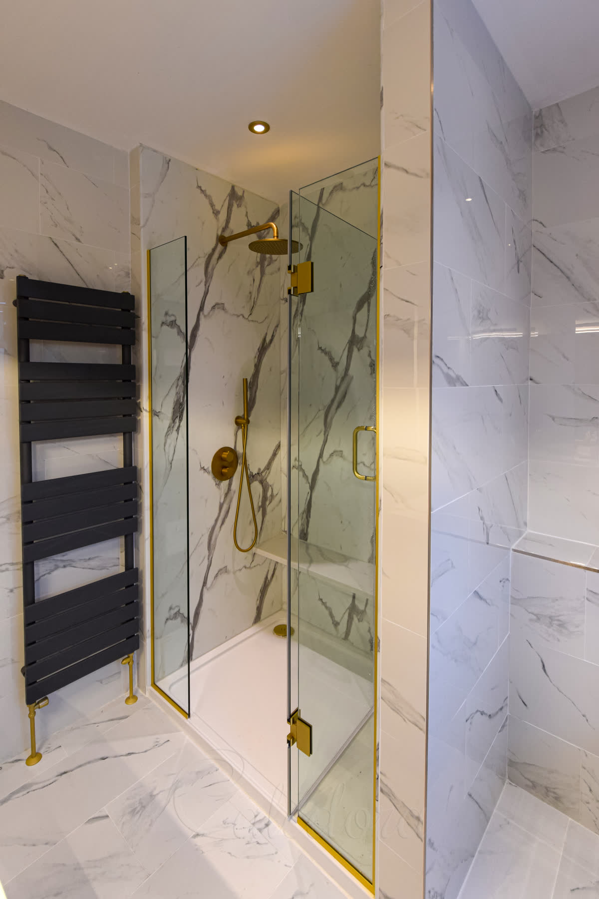 Interior view of brushed brass shower screens and door with gold shower controls