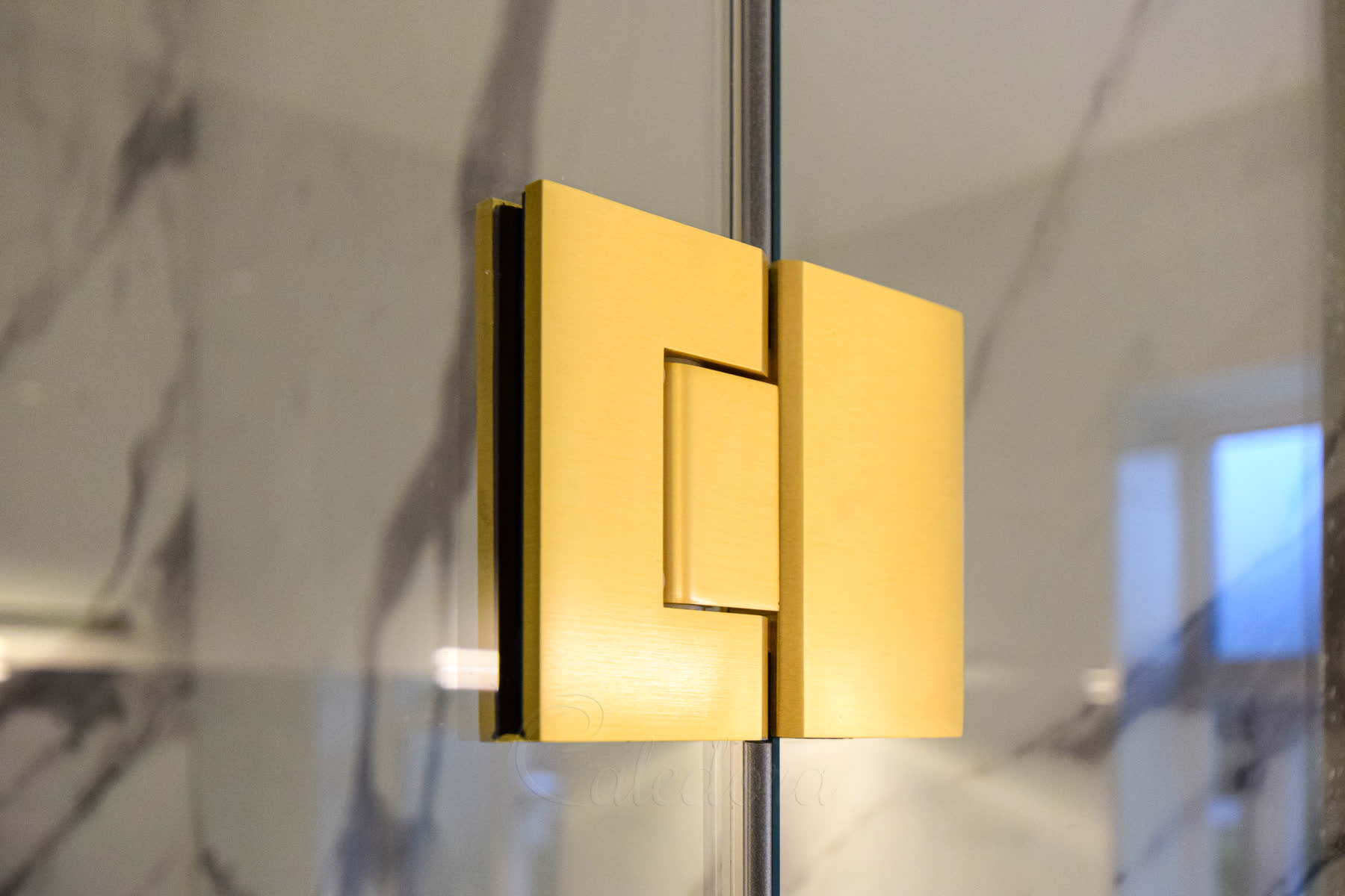 Close-up of brushed brass hinge connecting shower screen to glass door