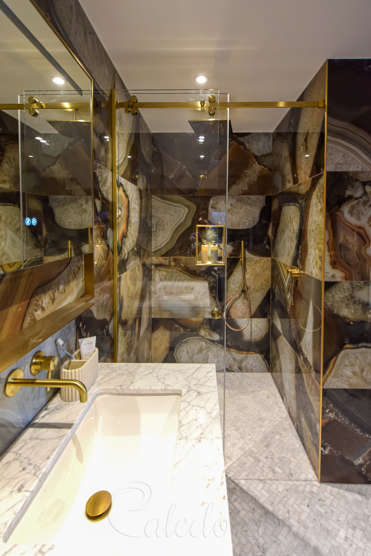 Elegant frameless sliding shower door with brushed brass hardware and U-channel fixing in a Bedford bathroom