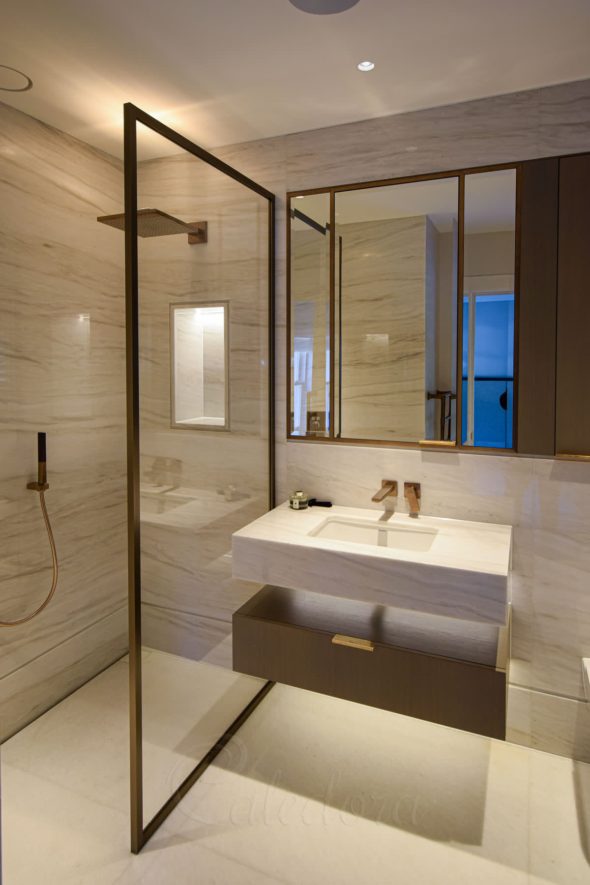 Full view of walk-in shower screen with bronze frame alongside marble vanity unit and stone floor