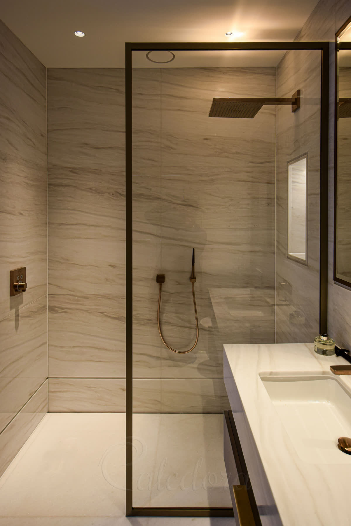 Brushed bronze framed shower screen with ultra clear glass and marble walls in London bathroom