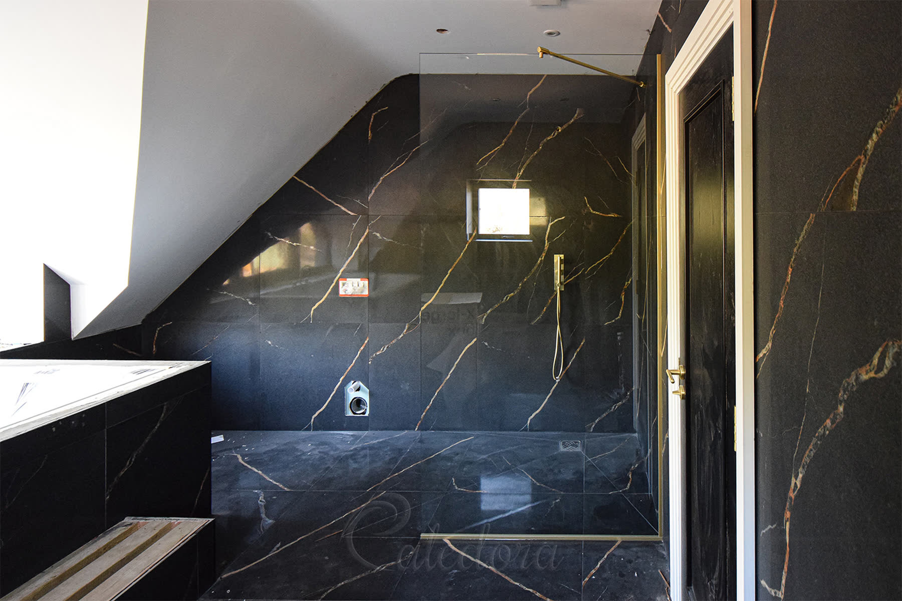 Completed walk-in shower screen installation with brushed brass hardware under sloped ceiling
