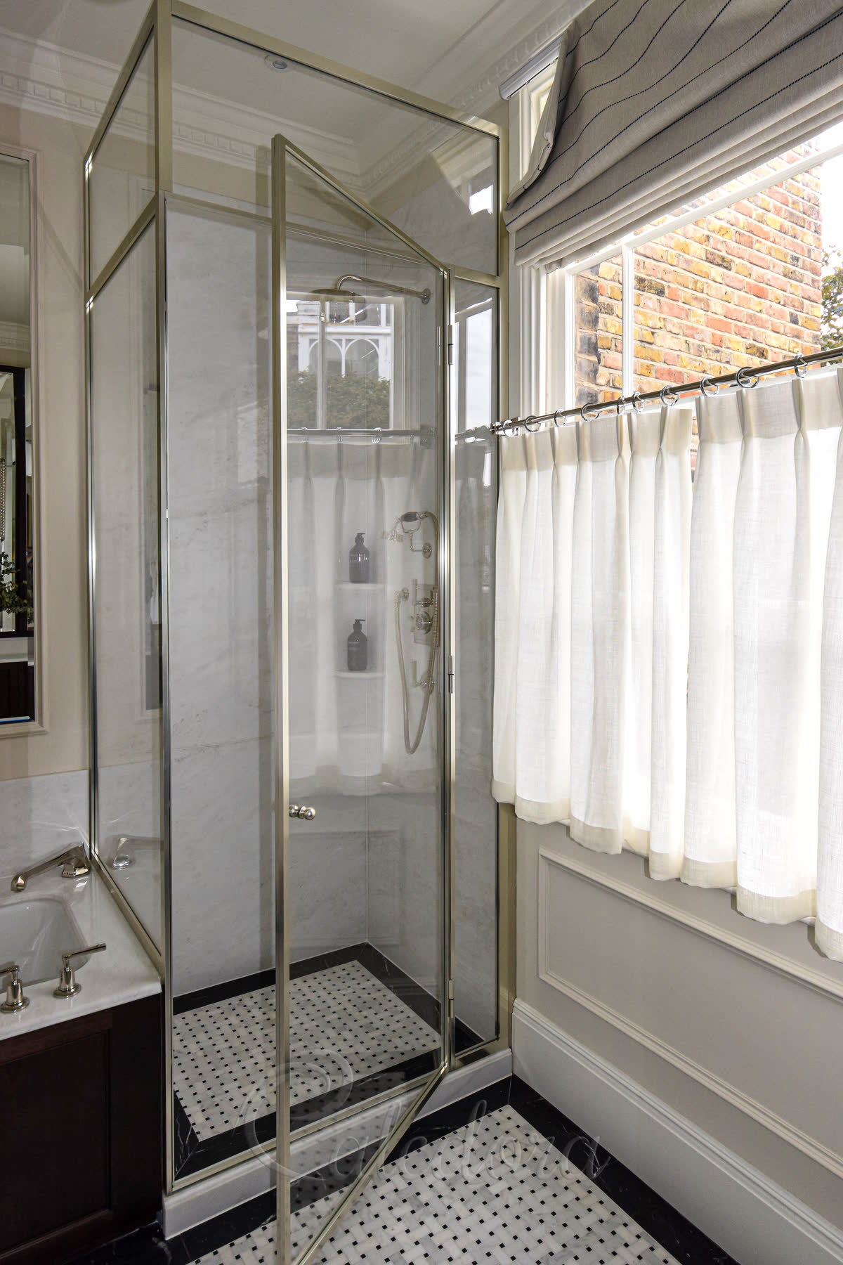 Corner shower enclosure with nickel frame and door opened to show marble interior