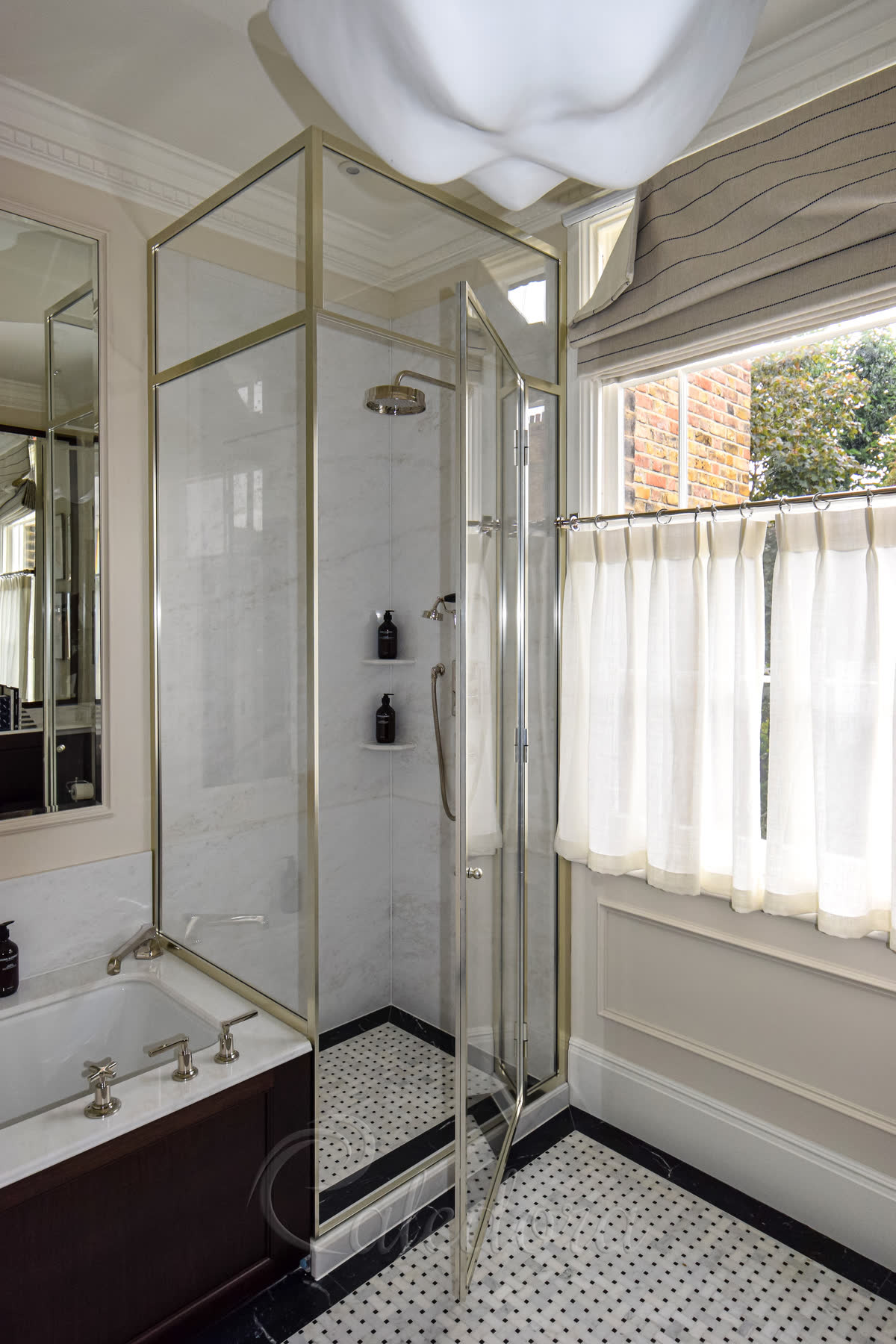 Fully framed nickel shower enclosure next to bath with mosaic marble tray