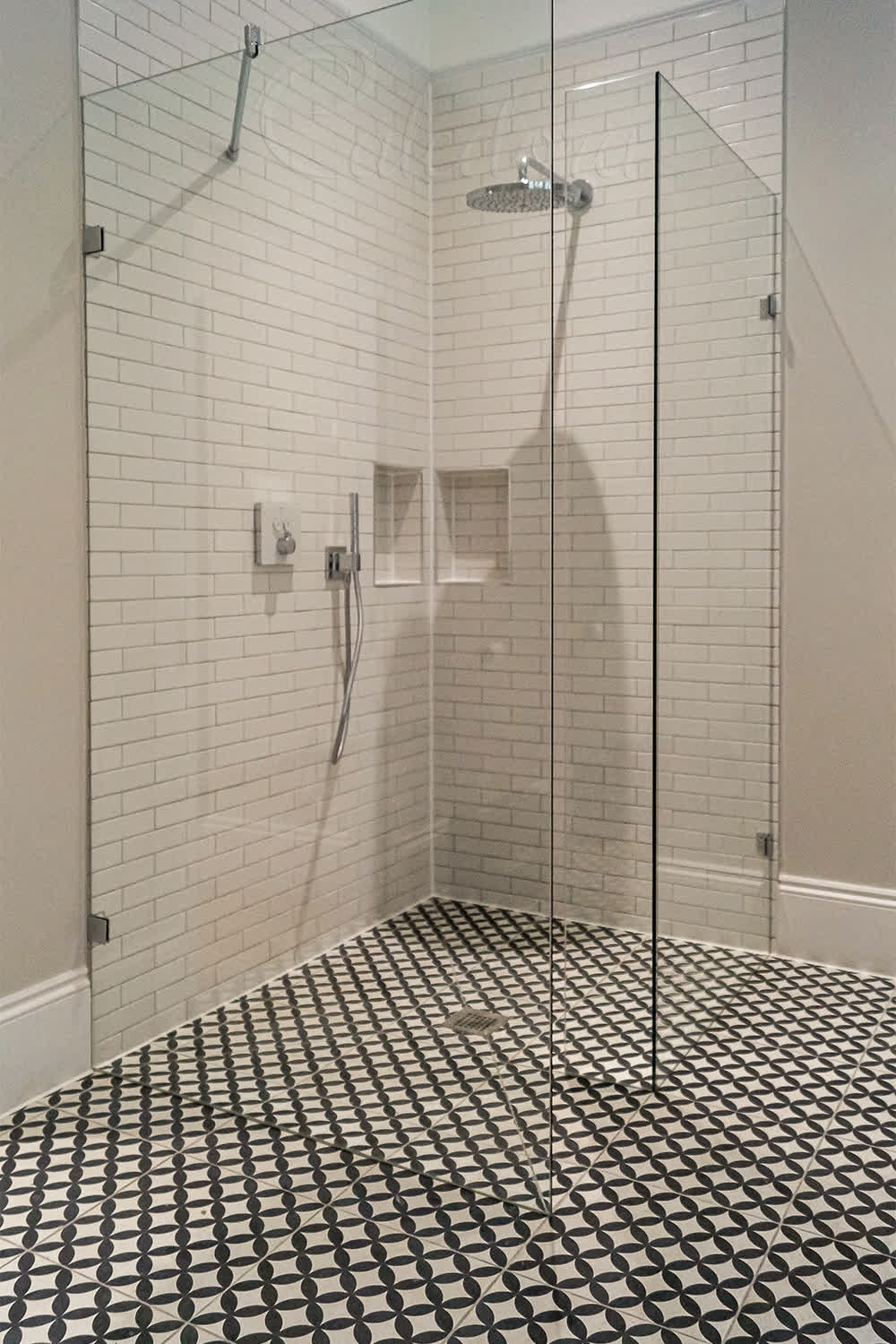 Corner walk-in shower with L-shaped glass panels and extra water protection screen in white tiled bathroom