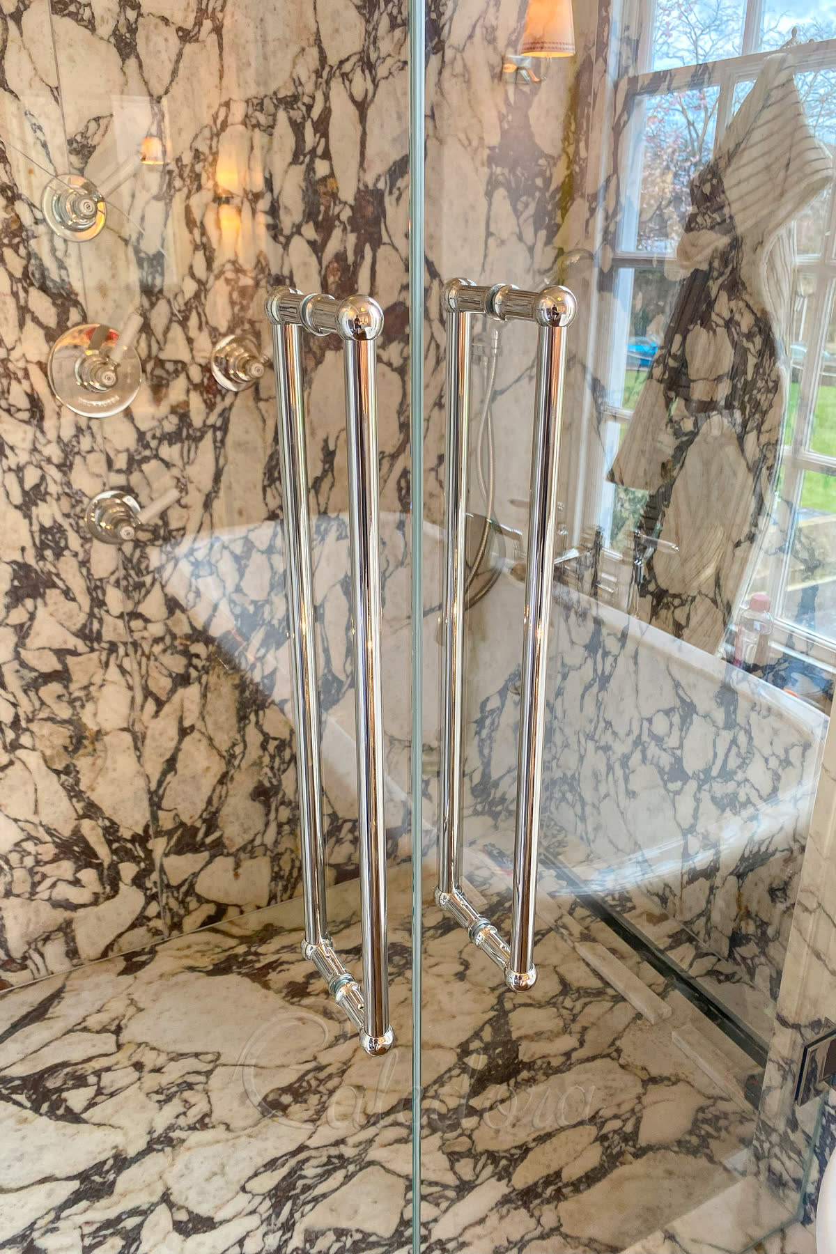 Close-up view of polished nickel handles and door seals on double shower doors