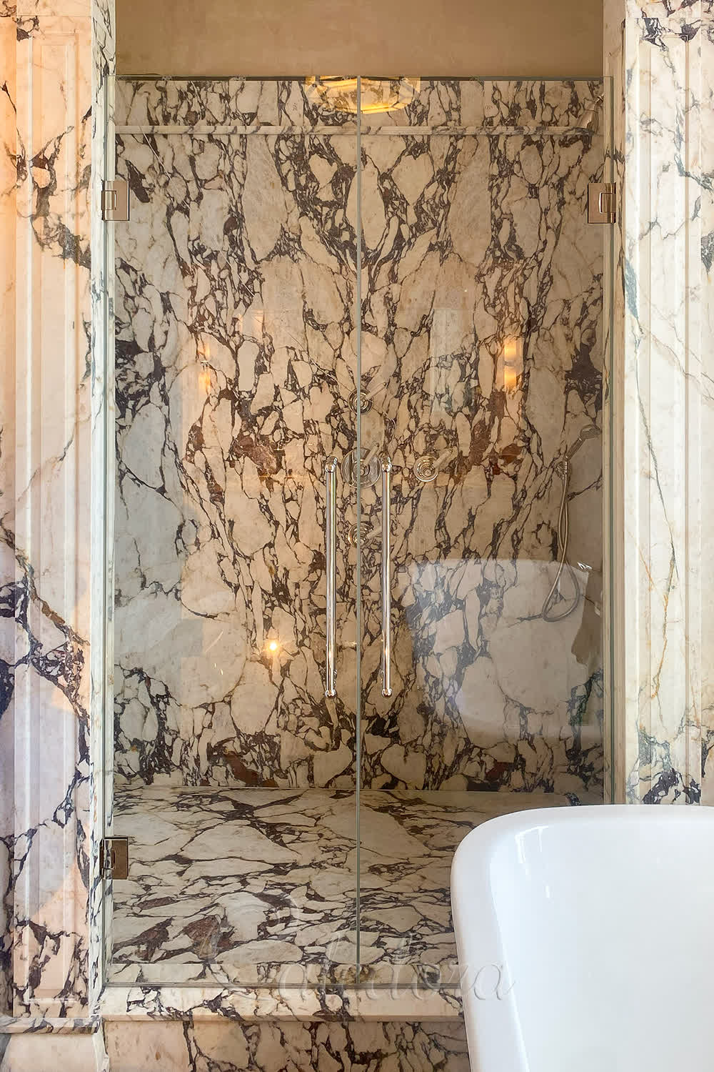 Double shower doors with flush-integrated hinges in marble stone walls