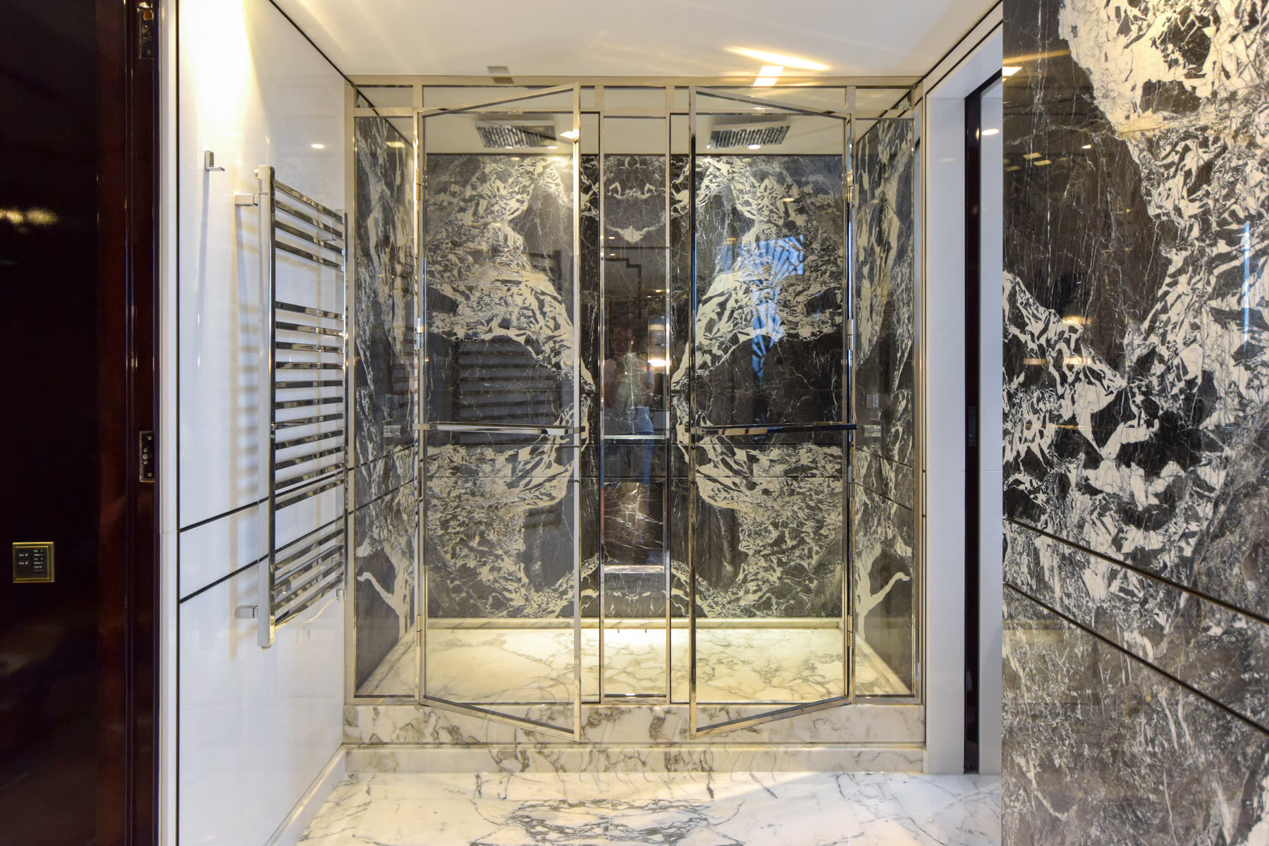 Double shower doors with twin towel rails and two shower heads visible inside
