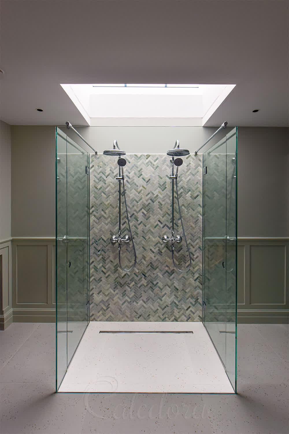 Inside view of double shower enclosure showing twin shower heads, herringbone tiles, and circular hole handles