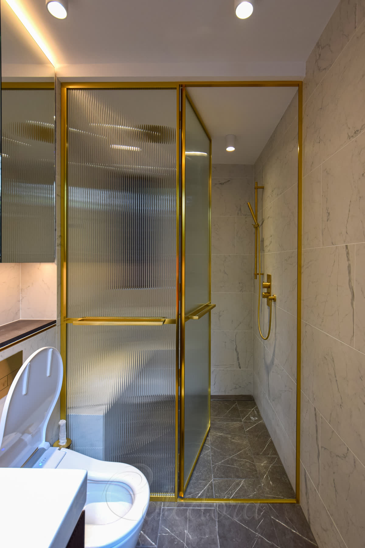 Fluted glass shower door framed in polished brass with full perimeter frame and fixed side panel