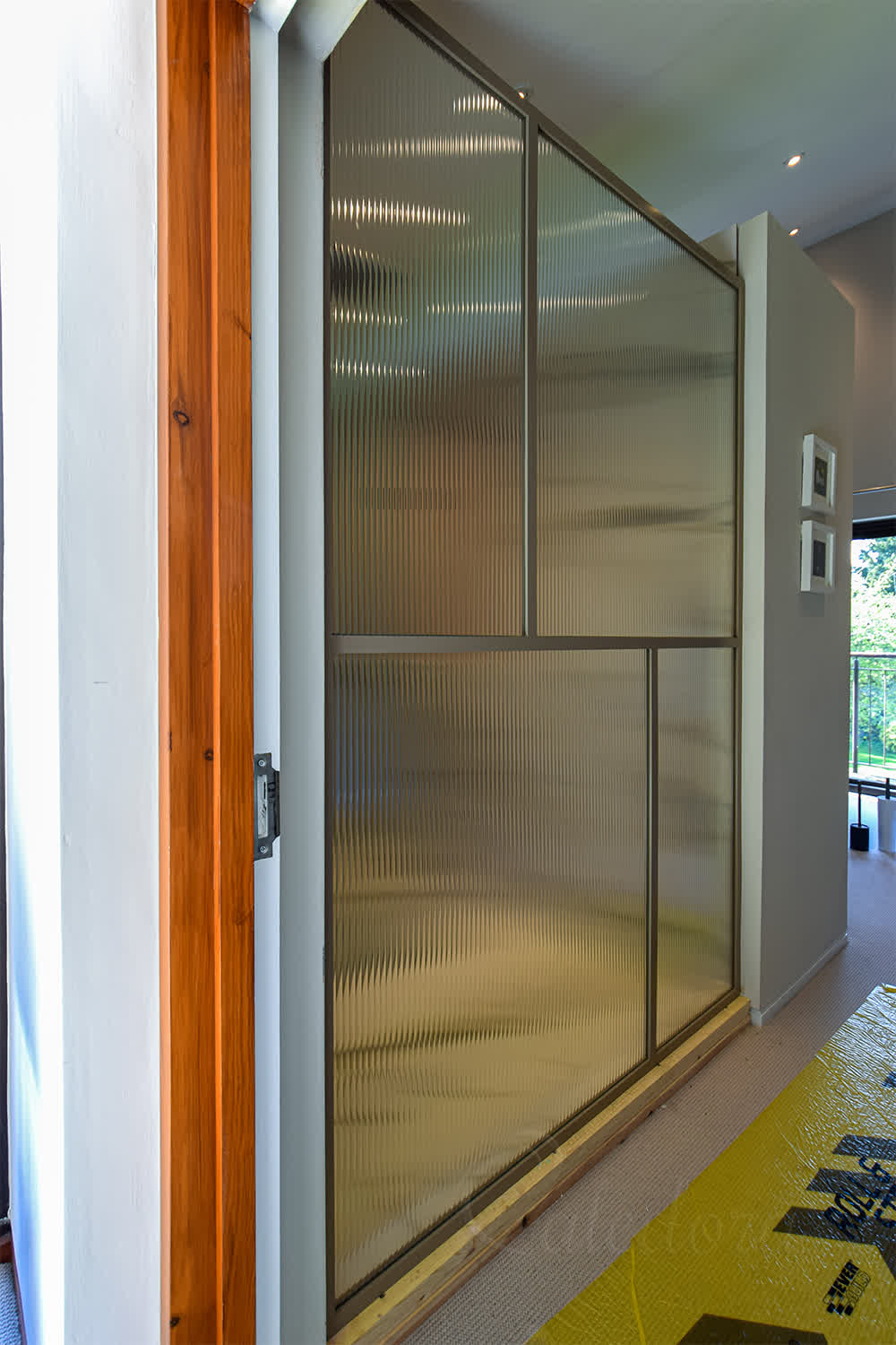 Bronze framed fluted shower screen with grid pattern viewed from bedroom side, serving as an elegant room divider