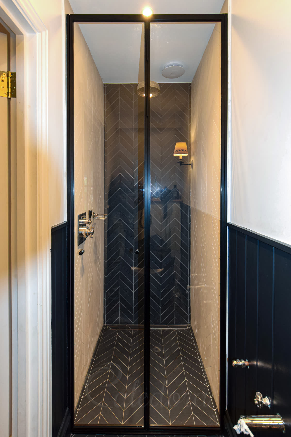 Closed black frame folding shower door with clear glass in narrow bathroom