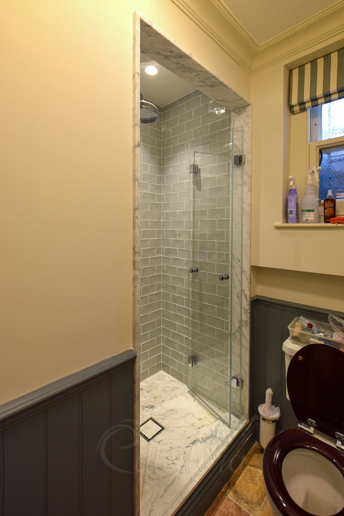 Folding shower door for small bathroom with grey-green tiles and chrome hardware