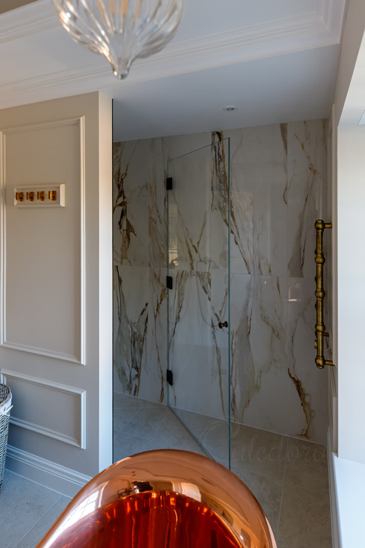 Antique brass frameless shower door half opened showing swing operation and towel rail