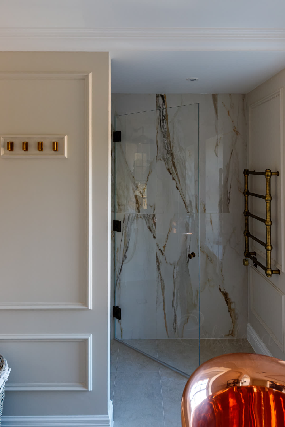 Antique brass frameless shower door fully opened revealing towel rail positioning and bathroom layout