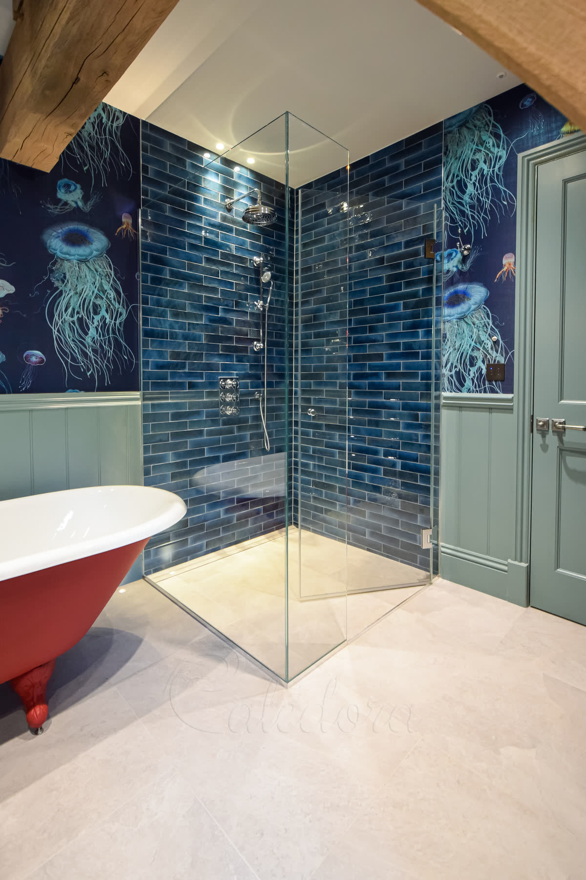 Hinged door frameless shower enclosure with chrome fixtures opening inwards in blue tiled bathroom