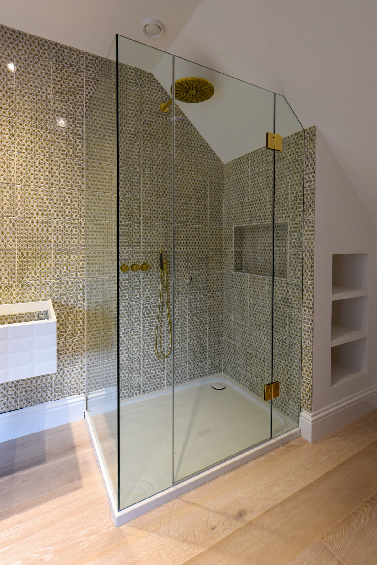 Brass fixtures and tile-aligned glass in frameless loft shower
