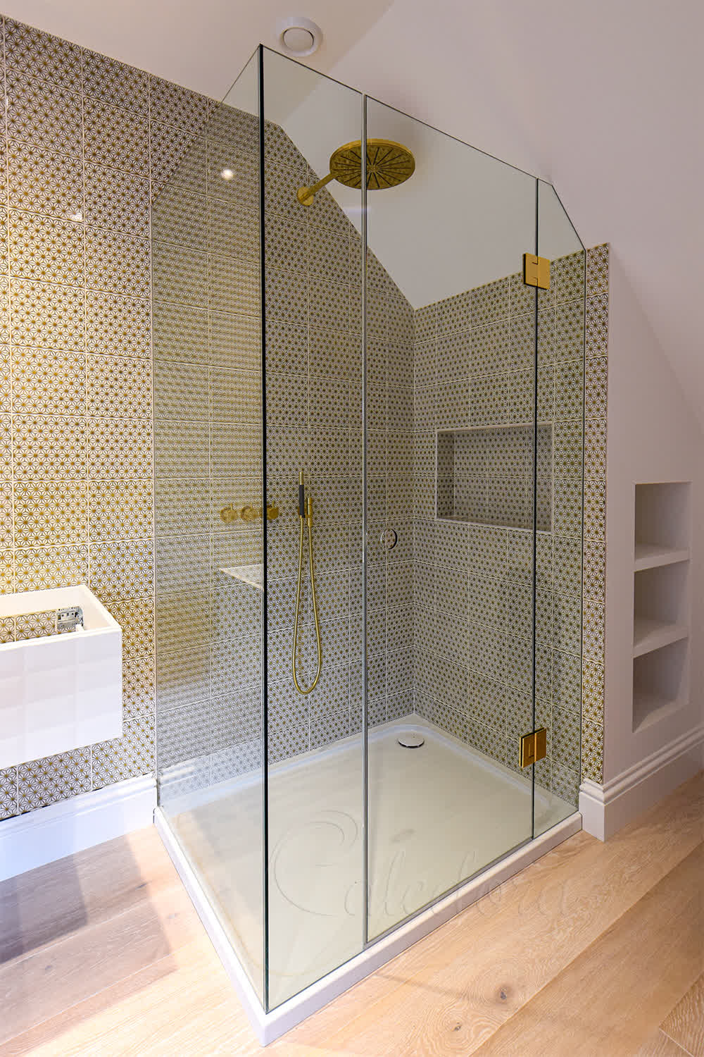 Custom frameless loft shower fitted under sloped ceiling with brass details