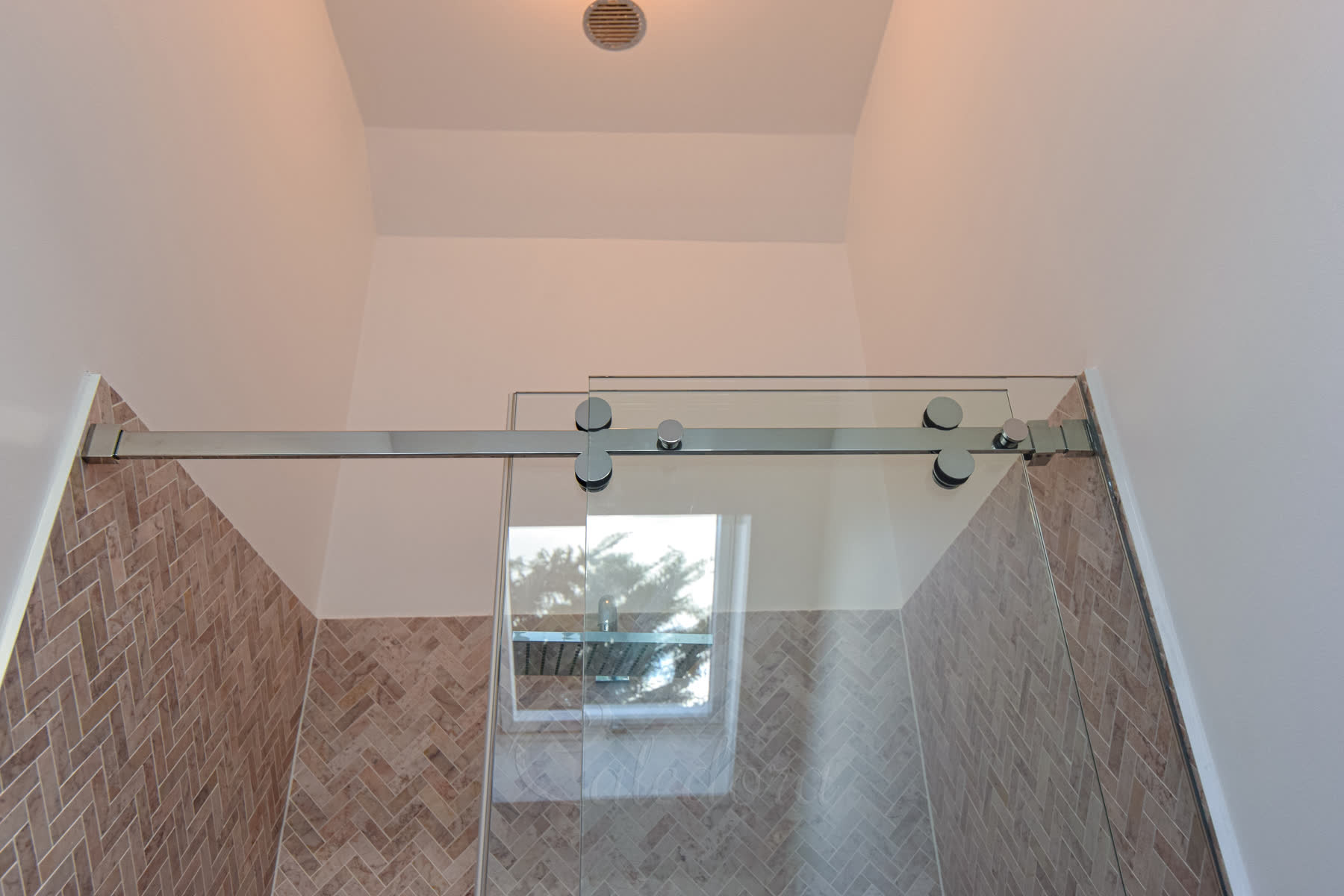 Chrome sliding track system with rollers supporting both fixed panel and sliding door with visible hardware