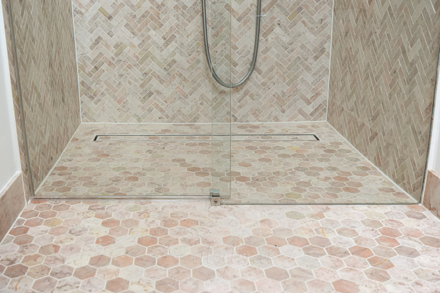 Walk-in shower floor showing door guide and angled glass edges to accommodate curved wall surfaces