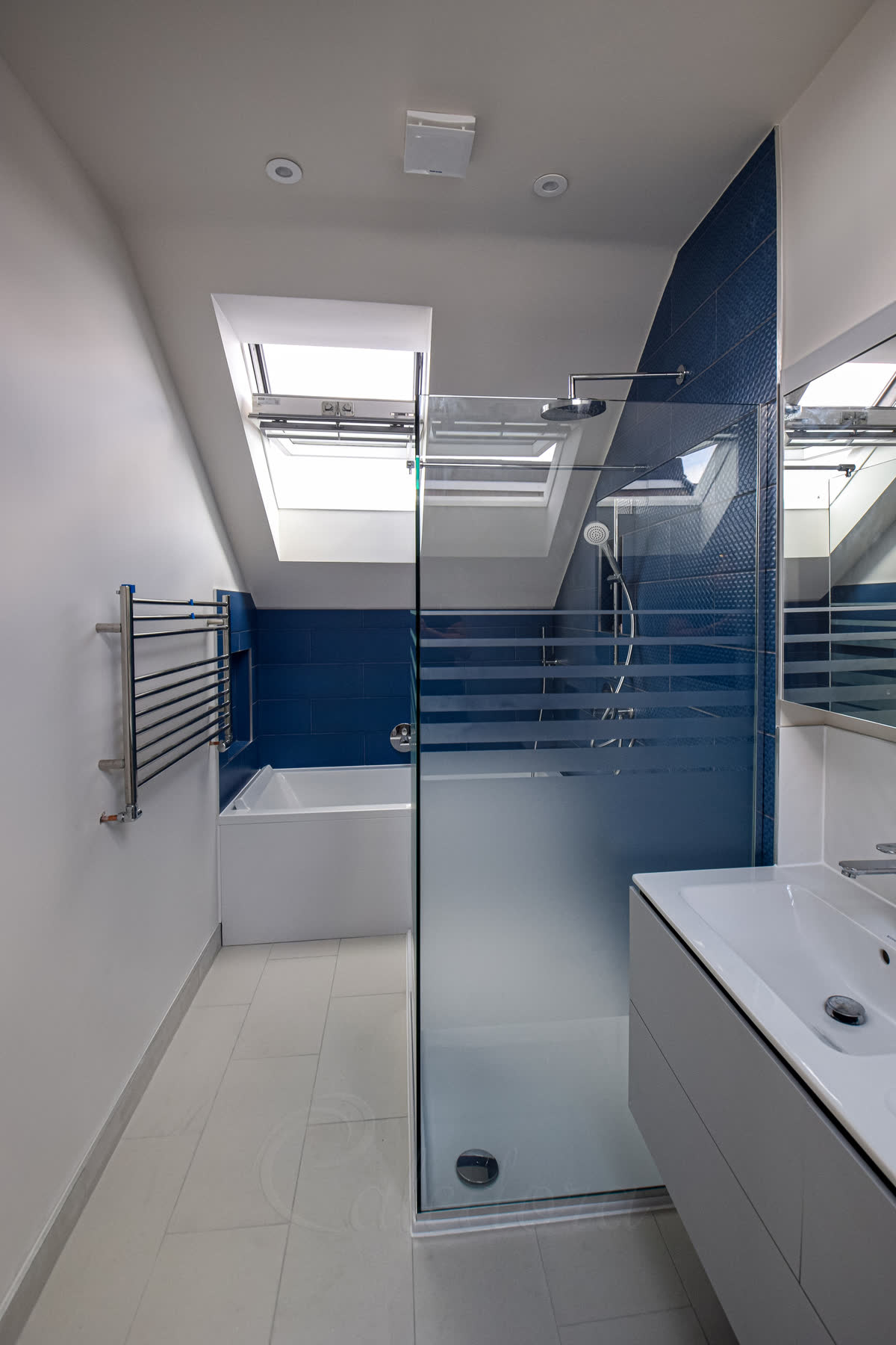 Wider view of frosted patterned walk-in corner shower screen under skylights
