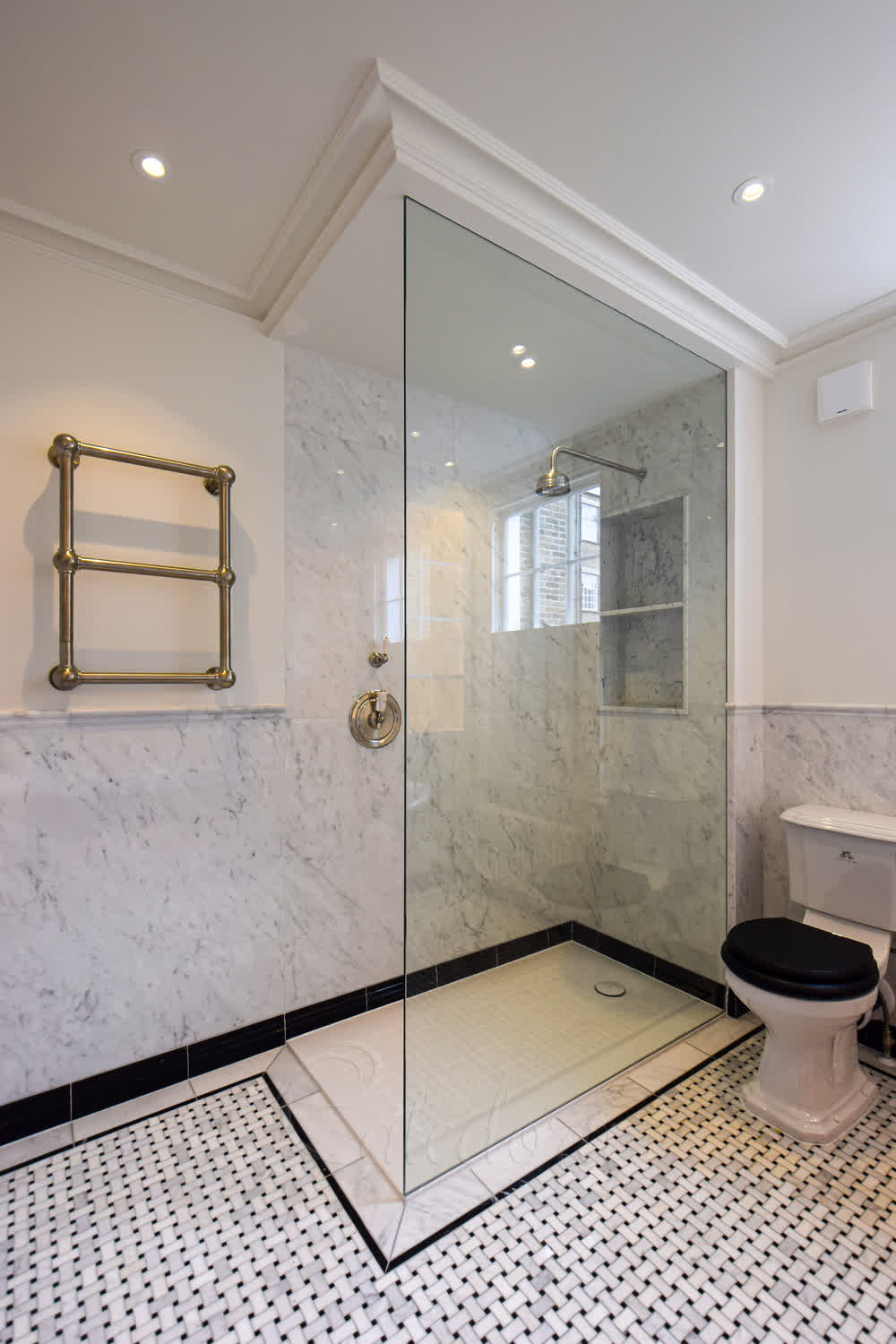 Full height walk-in shower screen recessed between marble and plastered wall with no visible frame