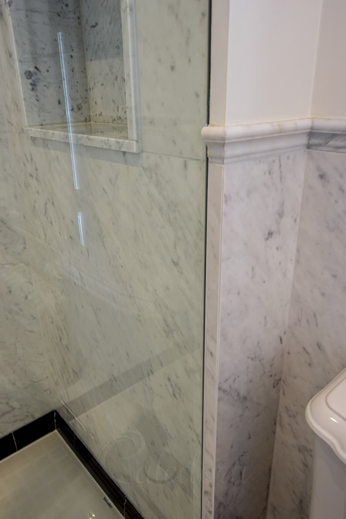 Large format frameless shower glass recessed into a tight wall space with minimal clearance