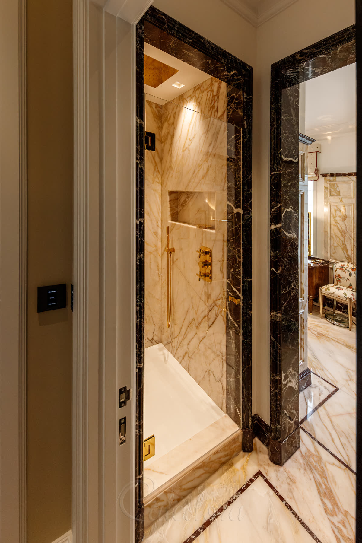 Gold shower door in closed position highlighting matching gold controls and marble walls in luxury London bathroom