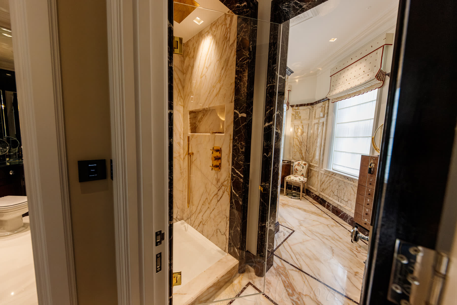 Wide view of gold shower door installation in stunning luxury London bathroom with complete marble design coordination