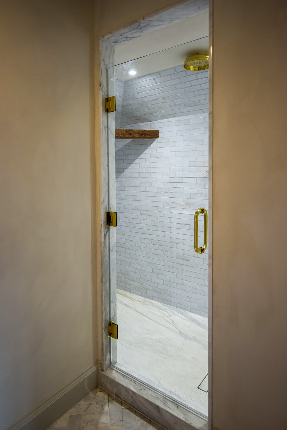 Gold shower door with polished gold hinges and white subway tiles in Mayfield bathroom