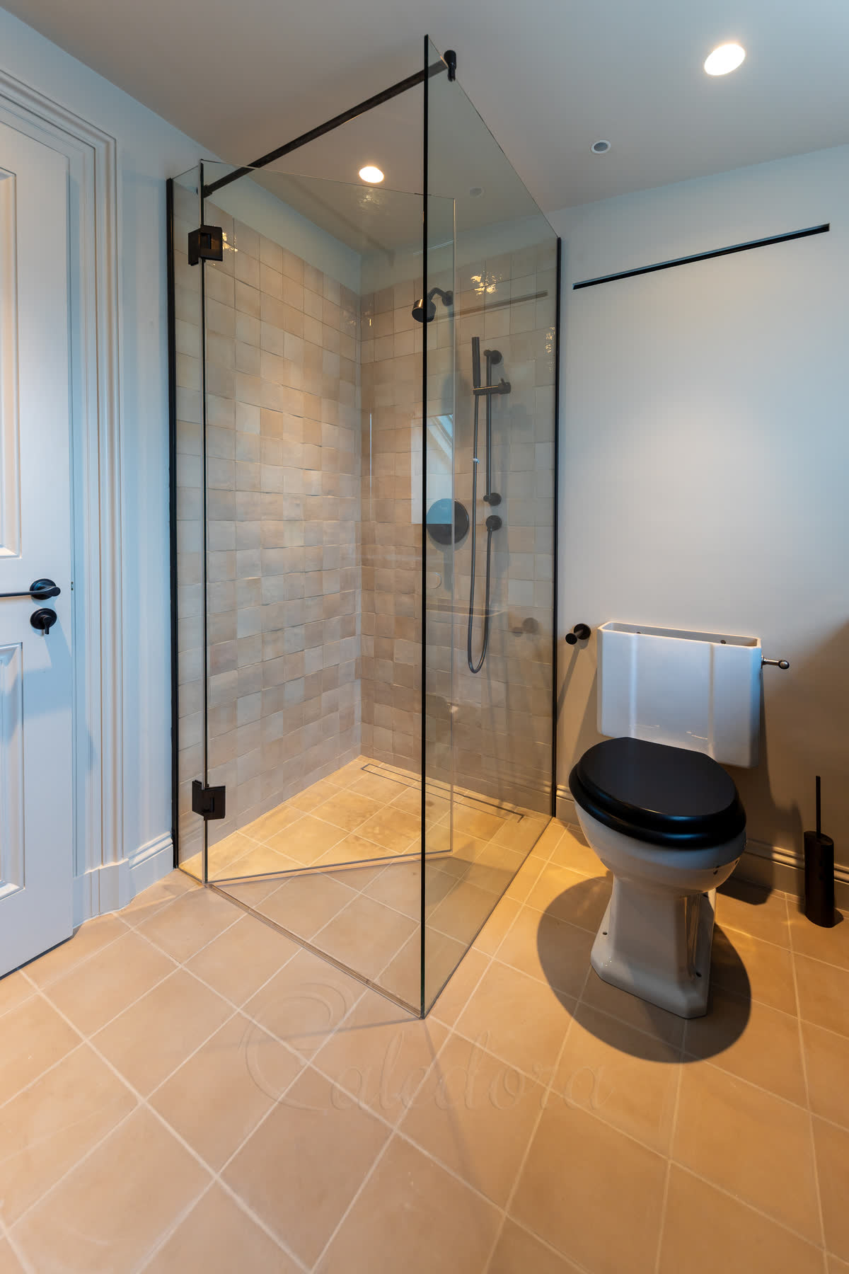 Corner gunmetal shower enclosure showing U-channel wall mounting and reinforcement arm