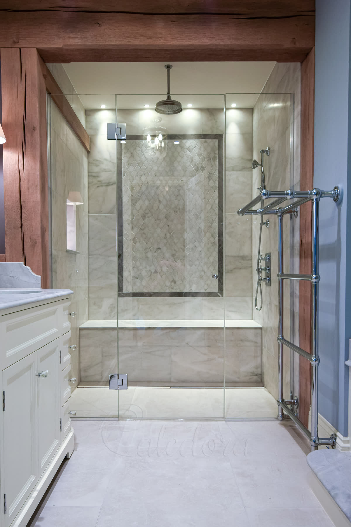 Frameless hinged shower door with chrome hinges shown closed in tiled Beaconsfield bathroom