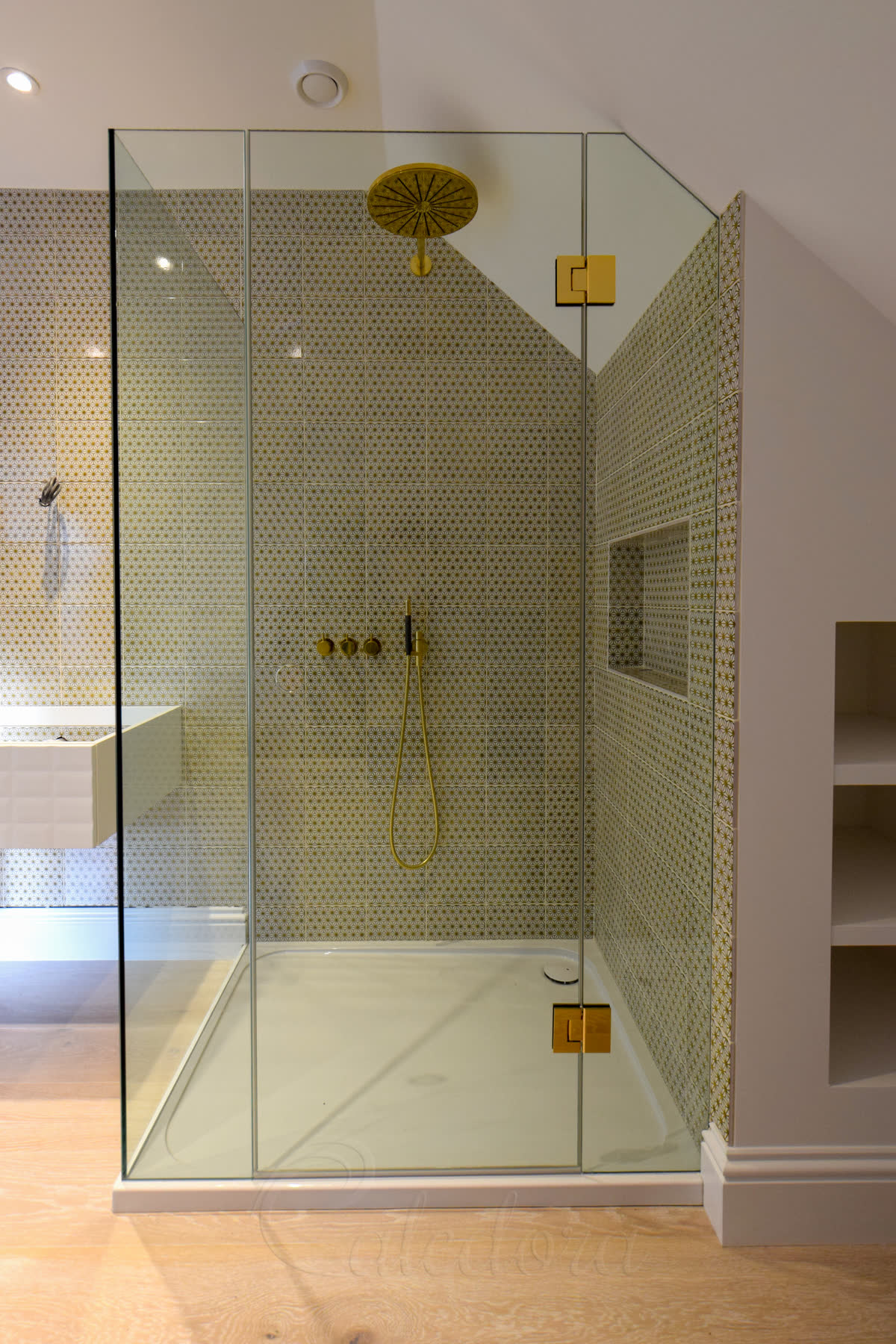 Frameless loft shower enclosure fitted under a pitched roof with fixed return and wall-hinged door