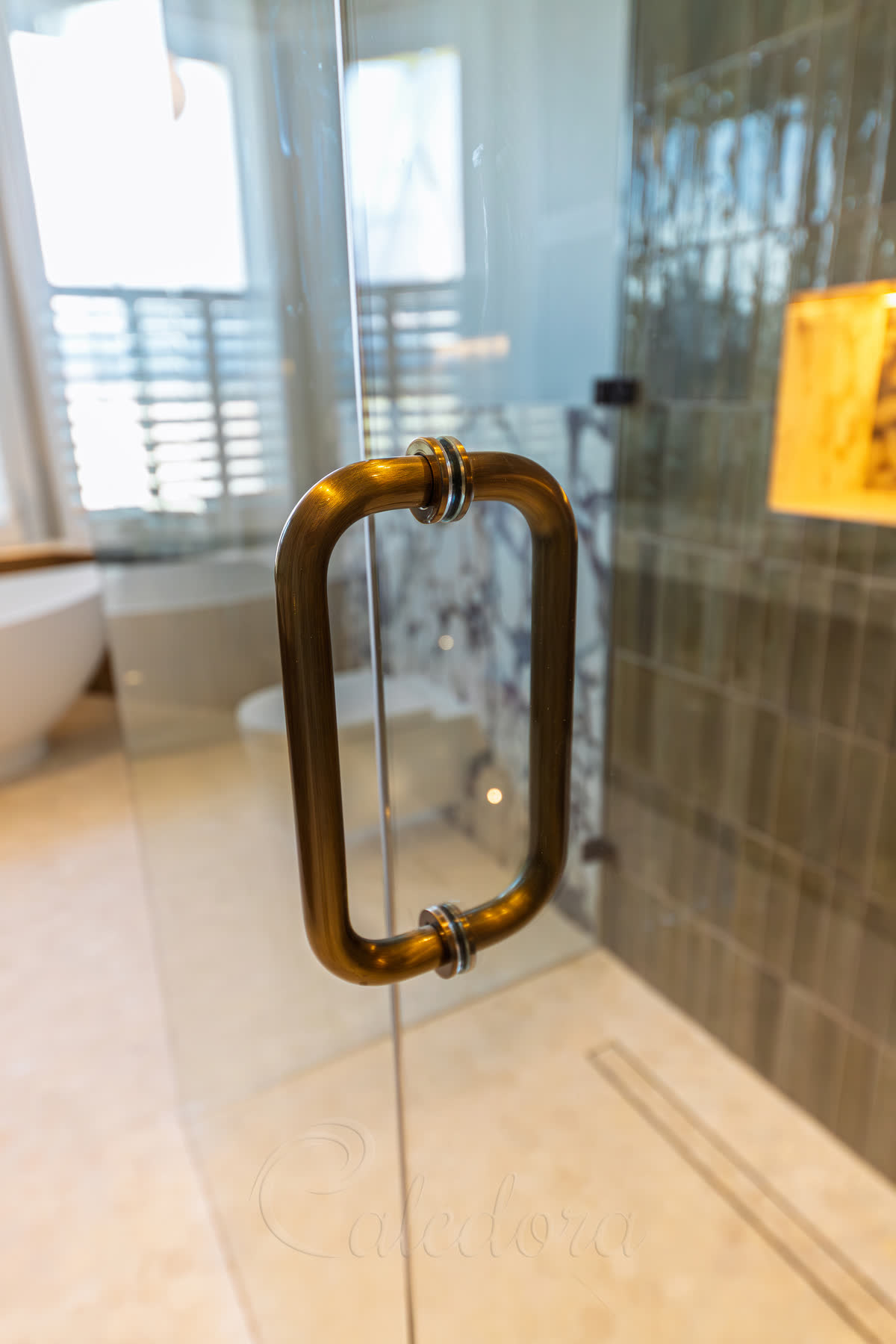 Antique brass door handle positioned at 1100mm height on frameless shower door