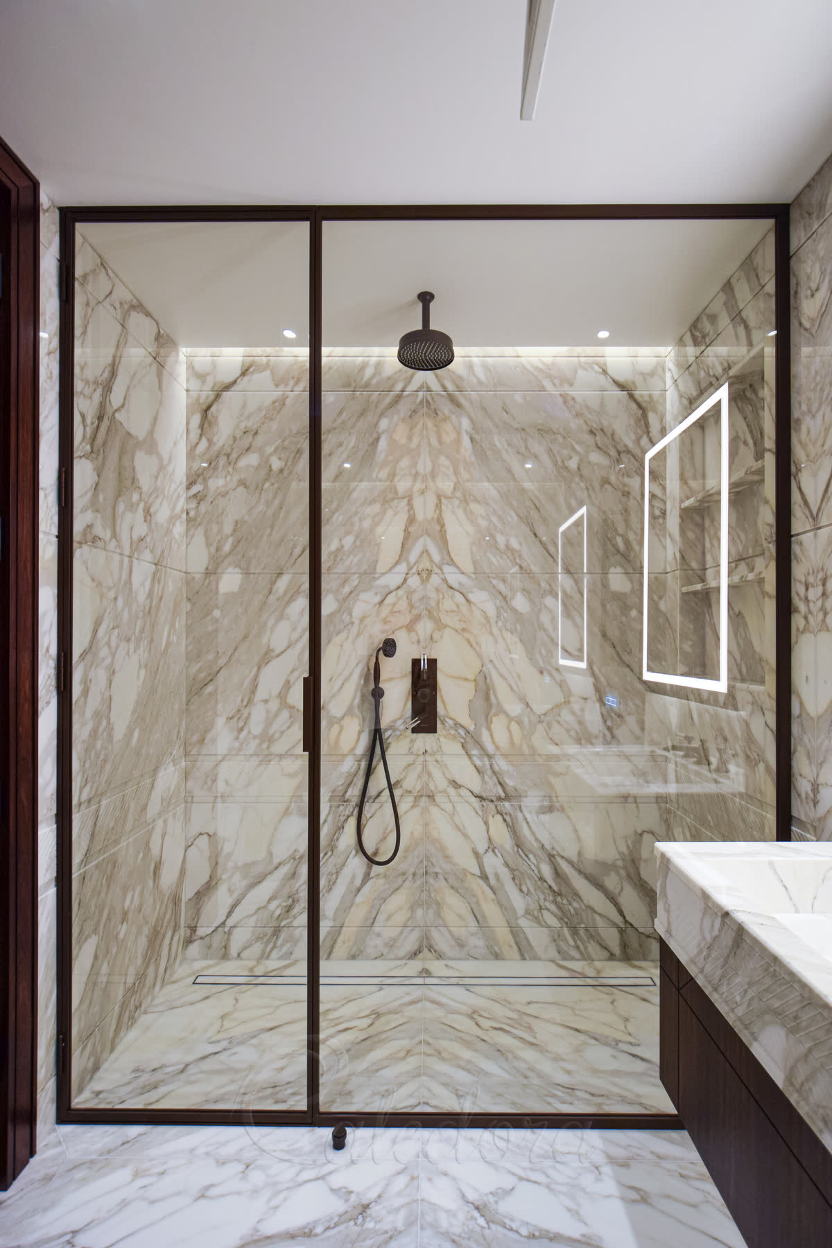 Full height bronze shower enclosure with satin finish and hinged door