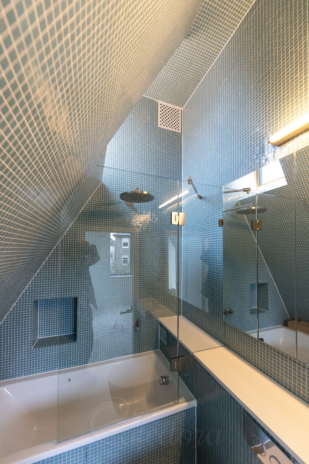 Bath screen for a sloping ceiling with CNC notch cut to fit around the protruding boxing and corian shelf, top reinforcement bar visible