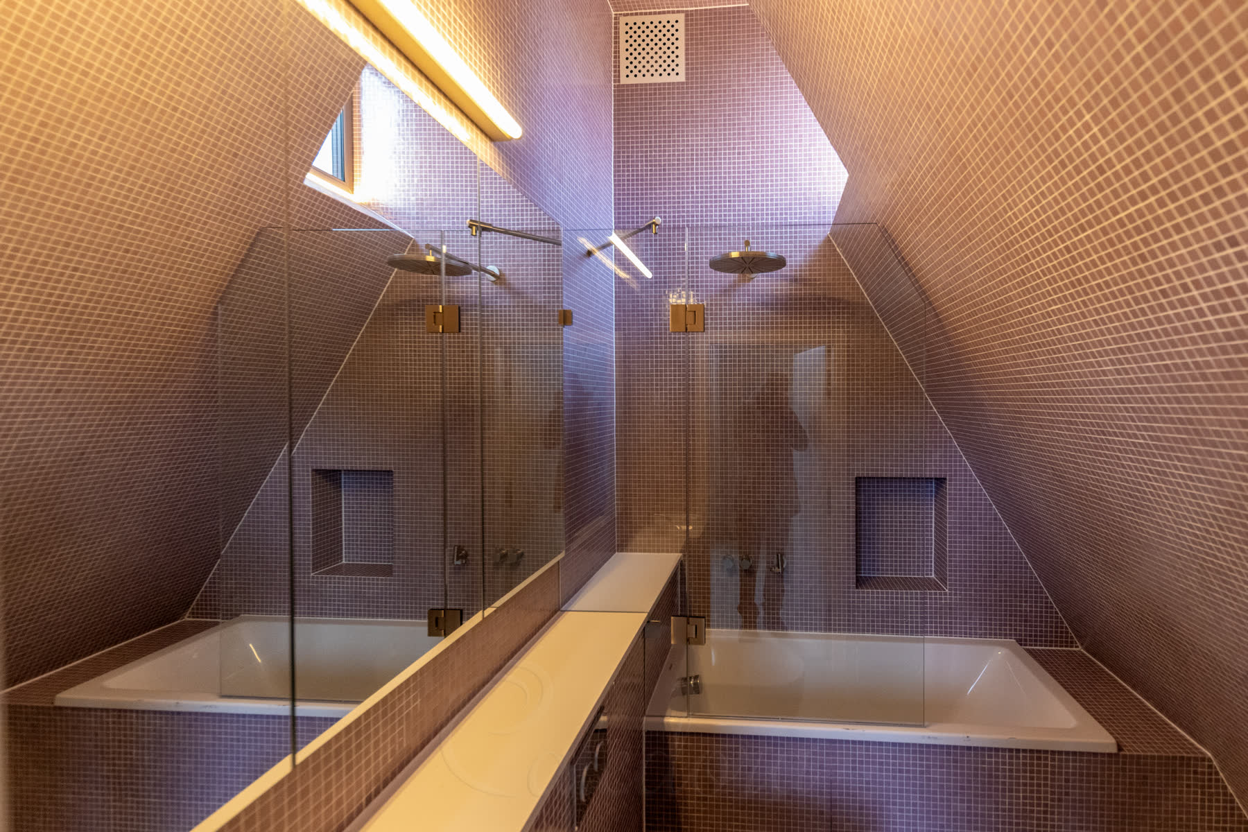 Wider view of the purple loft bathroom showing the bath niche, corian shelf, basin and bath screen with sloped ceiling