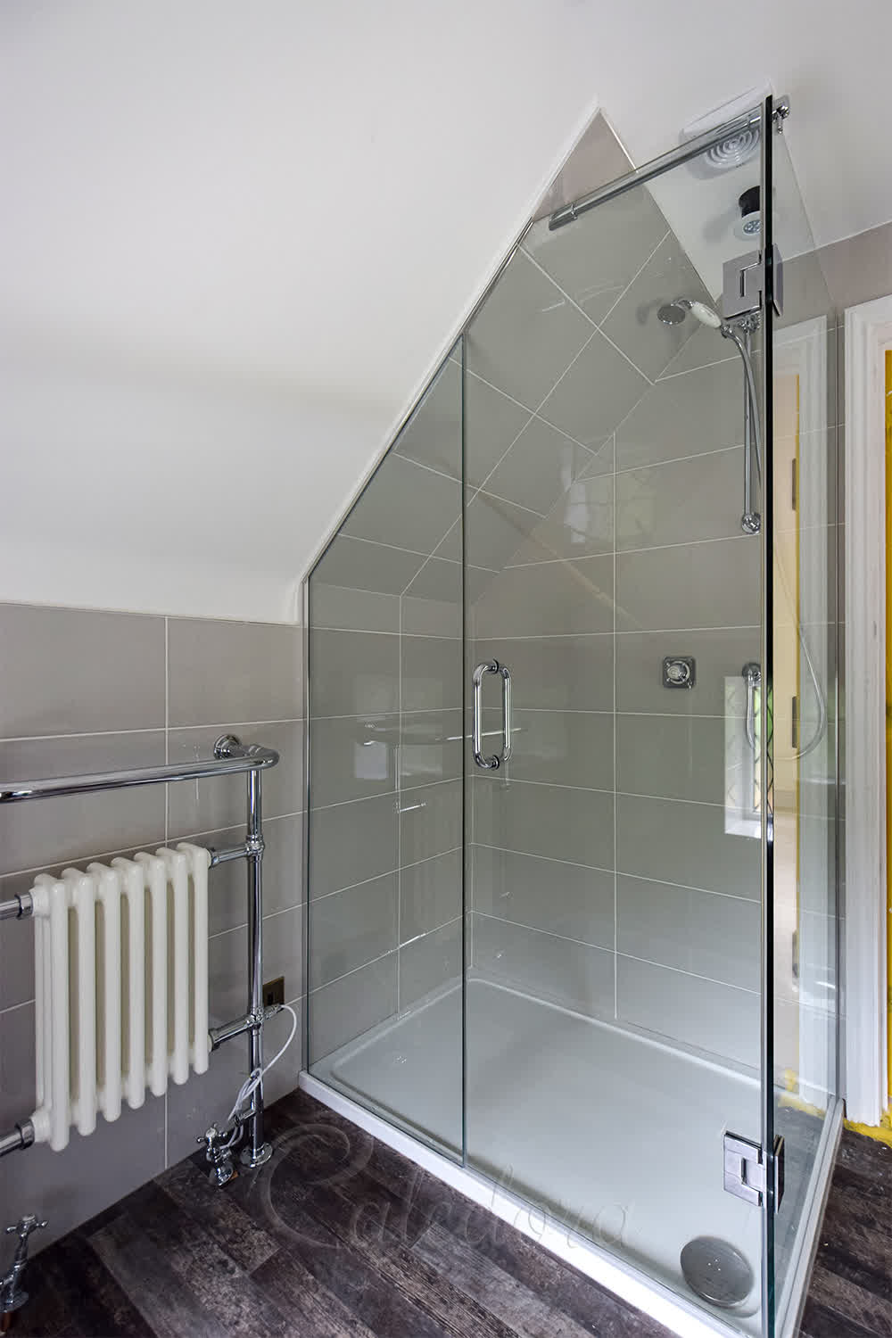 Loft shower enclosure with sloped ceiling and chrome reinforcement arm