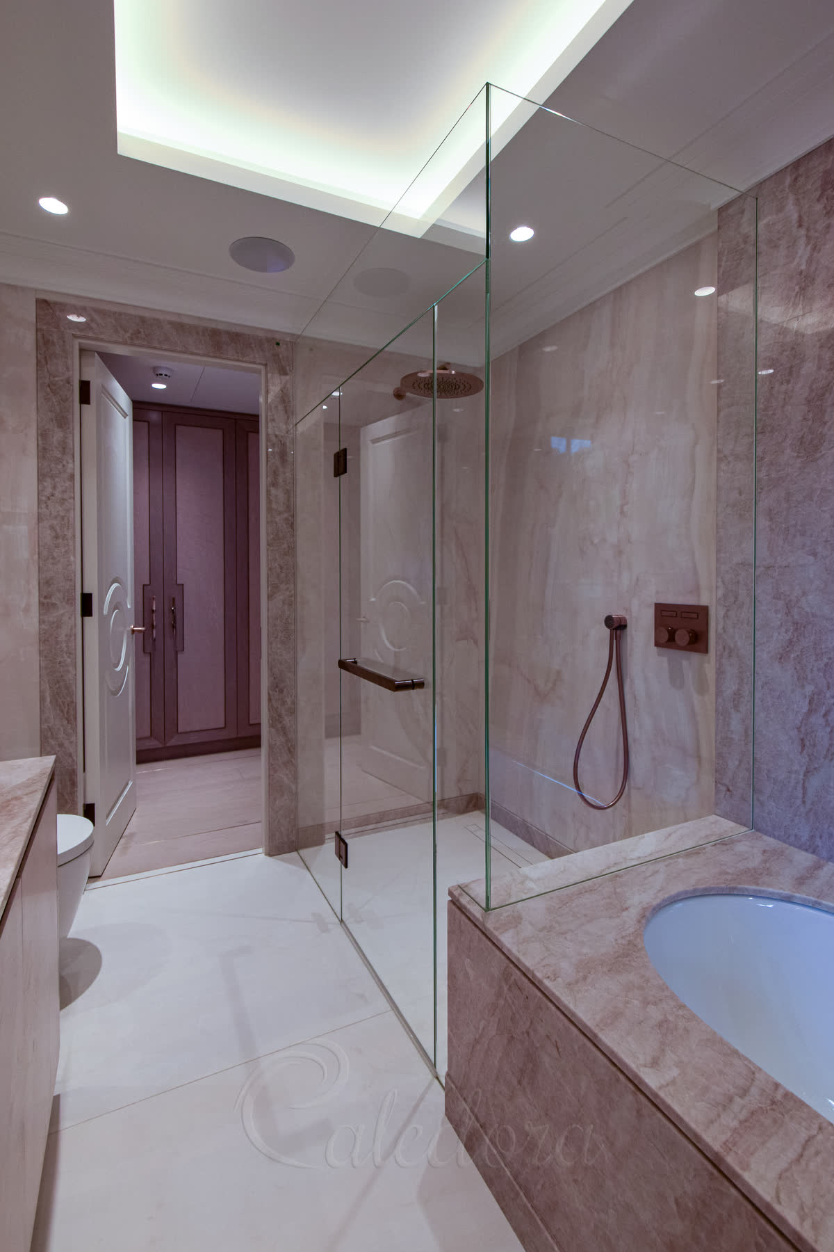 Full view of luxury bathroom with corner shower enclosure, marble tiling and modern lighting